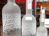 Trois bouteilles de vodka Belvedere sont posées sur une table devant un mur rouge.
