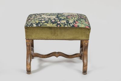 a green upholstered foot stool with a floral upholstered seat