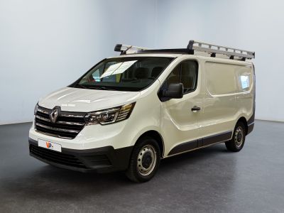 La camionnette blanche est garée dans une grande pièce au sol noir.