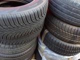 several tires are stacked on a pallet in front of a yellow truck