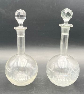 pair of clear glass decanters on a black surface