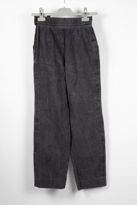 a black pants hanging on a hanger against a white wall