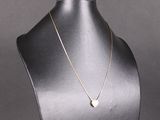 un collier en or sur un mannequin, orné d'un pendentif en forme de cœur