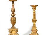 pair of antique brass candlesticks on pedestals against a white background
