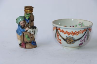 une petite tasse et une petite figurine posées l'une à côté de l'autre