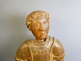 une statue en bois représentant une femme assise sur une table
