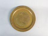 a gold plate with a design on it on a white surface