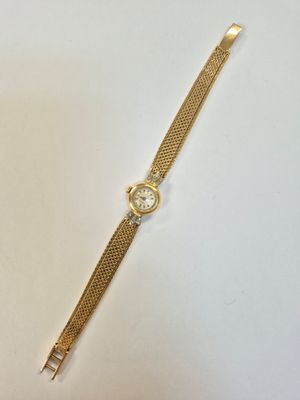 gros plan d'une montre en or sur une surface blanche