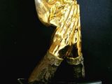 statue of a person holding a gold object on a black surface