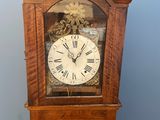 une horloge de parquet en bois dont le cadran est orné de chiffres romains