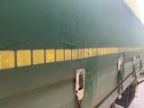 a green train car with yellow stripes on the side of it