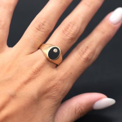 the woman is wearing a gold ring with a black stone on it