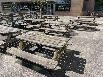 de nombreuses tables de pique-nique en bois devant un bâtiment