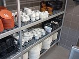 many plates and bowls on the shelves in the kitchen