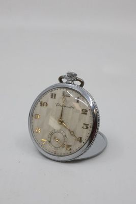 a silver pocket watch sitting on top of a white table