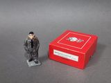 une petite figurine représentant un homme debout devant une boîte rouge