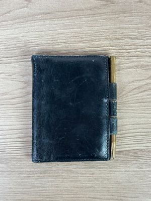 un portefeuille en cuir noir sur lequel est posé un stylo
