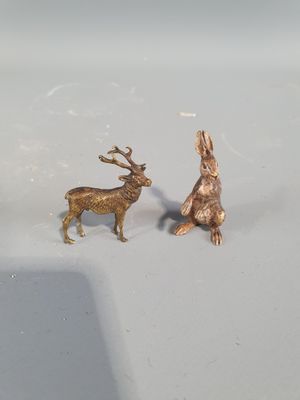 two figurines of a rabbit and a deer on a white surface