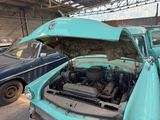 a blue car with a hood open in a garage