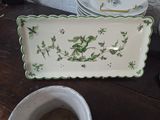 a white plate with green flowers on it next to a cup and saucer