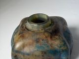a blue and brown vase sitting on a white surface