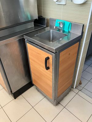 un évier dans un coin de la cuisine, à côté d'un réfrigérateur en acier inoxydable