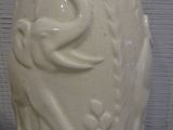 a white vase with a bird on it sitting on a table