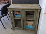 une petite armoire avec une porte vitrée et une chaise placée devant