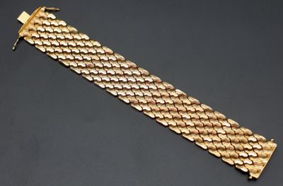 gros plan d'un bracelet en or sur une surface noire
