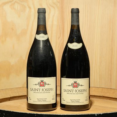 two bottles of wine sitting on top of a barrel next to each other