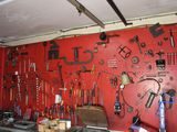 a red wall with a bunch of tools hanging on it