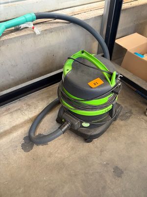 a green and black vacuum on the ground next to a box of boxes