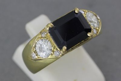 une image représentant une bague en or sertie d'une pierre noire entourée de diamants blancs