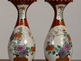 two vases sitting on a table with flowers in them