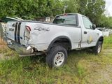 a truck that is parked in the grass by a fence