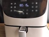 an air fryer sitting on top of a wooden table next to a black and white wall