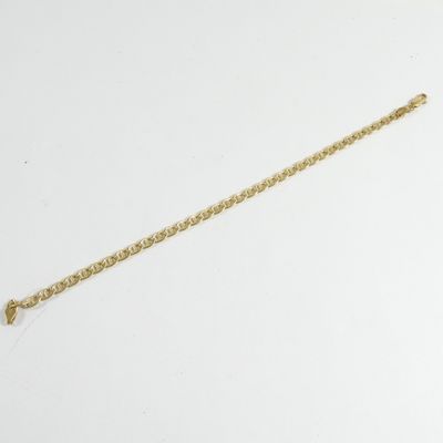 une photo d'un bracelet à chaîne en or posé sur une surface blanche