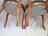 two wooden chairs with black upholstered seats on a white cloth