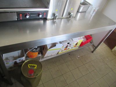 un plan de travail en acier inoxydable sur lequel est posé un faitout, dans une cuisine professionnelle