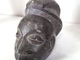 a black sculpture of a man ' s face with a hat on