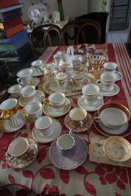 de nombreuses tasses et soucoupes posées sur une table recouverte d'une nappe rouge et blanche