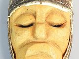 a wooden mask with a white face on a white surface