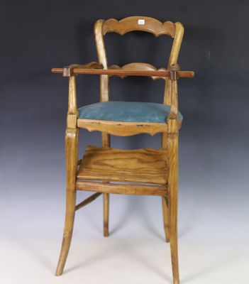 une vieille chaise haute en bois avec un siège bleu sur fond blanc