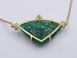 a close up of a green stone pendant on a gold chain