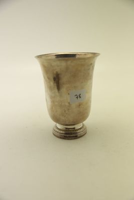 une coupe ancienne en argent posée sur un socle, sur une surface blanche