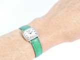 wrist shot of a woman wearing a green watch with a white face