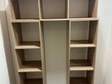 a wooden bookcase with several shelves in the corner of the room