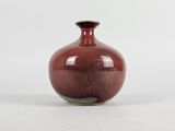 a red vase sitting on a white surface with a white background