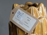 a yellow vase with a tag on it sitting on a table