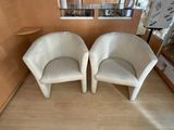 two white chairs sitting next to each other in a room